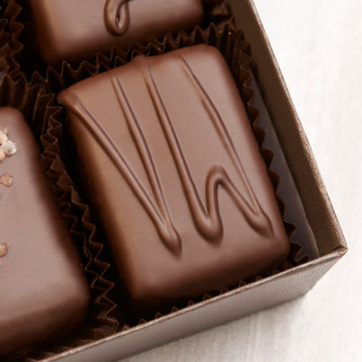A close-up of a chocolate square with the letters VW on it to signify it is vanilla with walnuts.