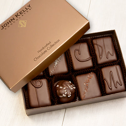 An open eight piece assortment. Various chocolates from the assortment can be seen. The lid of the box is partially on the box.