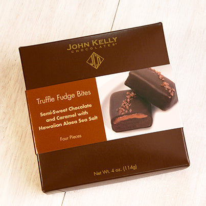 A dark brown box with a brown and white sleeve on it. The sleeve has an image of two red salted truffle fudge bites on it.