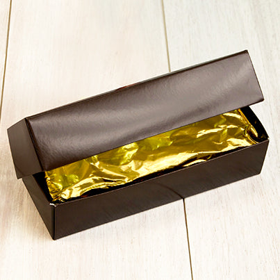 A dark brown box sits open with a gold wrapped bar in it.