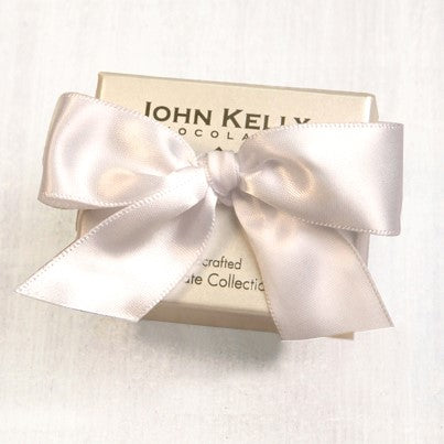 A cream colored small box. The box is tied closed with a white bow.