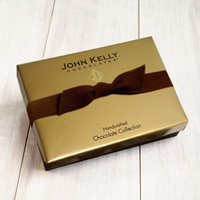 A gold box with a brown ribbon stretched around it.